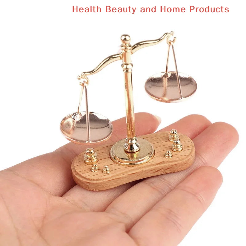 A vintage miniature balance scale with a brass frame and wooden base is held in a hand.