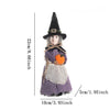 A small ornament featuring a witch hat, knitted clothing in purple and gray, and an orange accent.