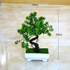 A small artificial bonsai tree with green foliage planted in a white rectangular pot.
