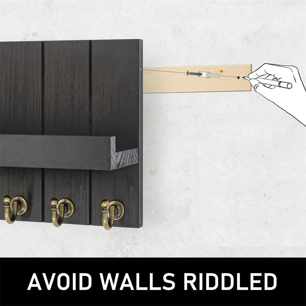 A hand is using a tool to mark a wooden piece, which is being placed onto a dark wood wall organizer with five brass hooks.