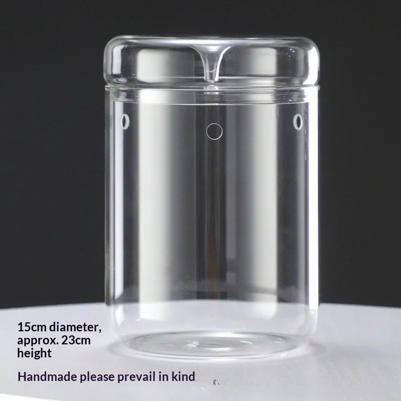 Clear glass cylindrical vase with a lid, used for decor.