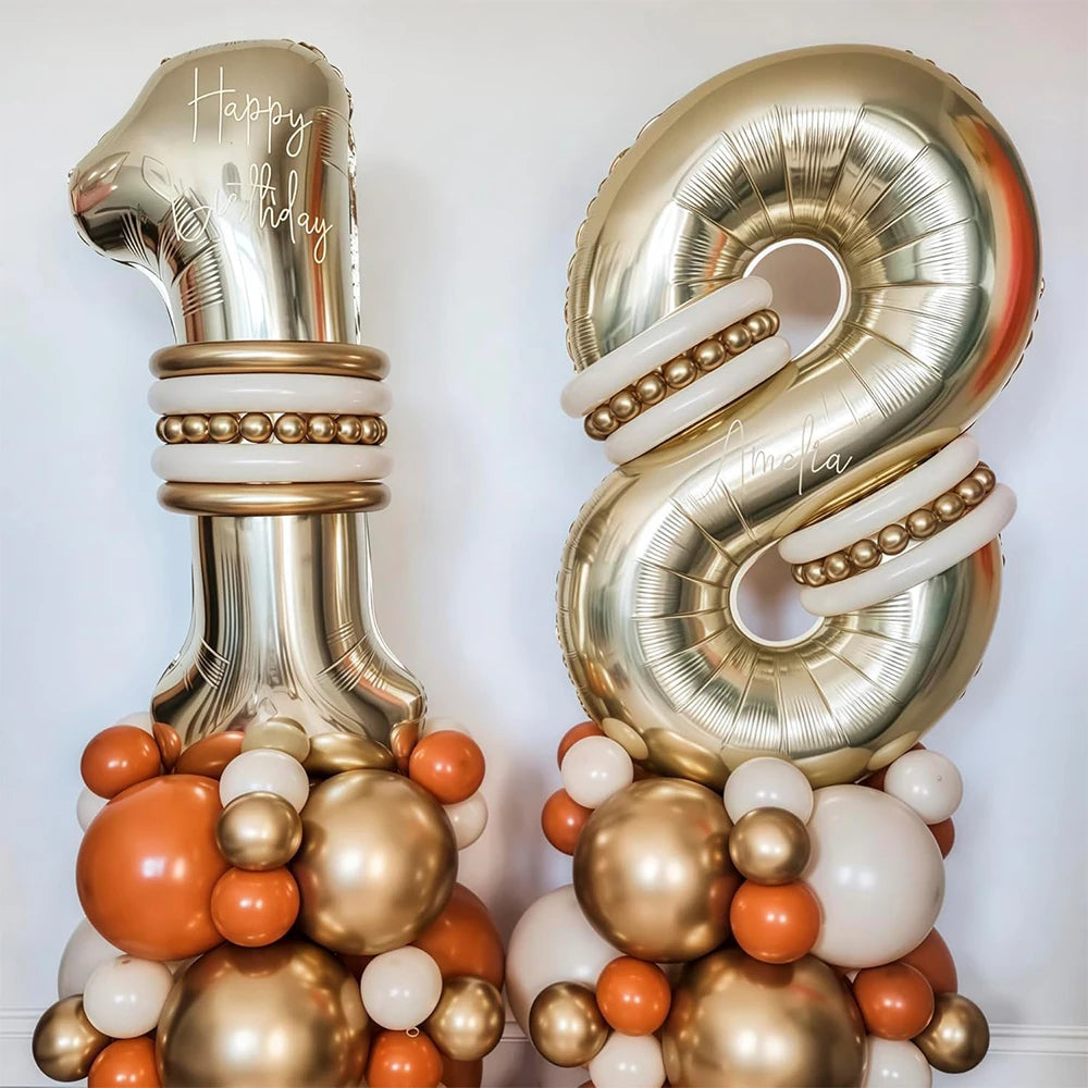 Two large gold foil number balloons, 1 and 8, decorated with tissue paper balls.