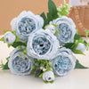 A bouquet of light blue silk peony flowers with green leaves and small buds.