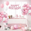 A display of pink and white latex balloons with metallic confetti accents set up for a birthday celebration.