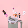 Reusable silicone straw covers shaped like Halloween ghosts and witches inserted into a reusable cup.