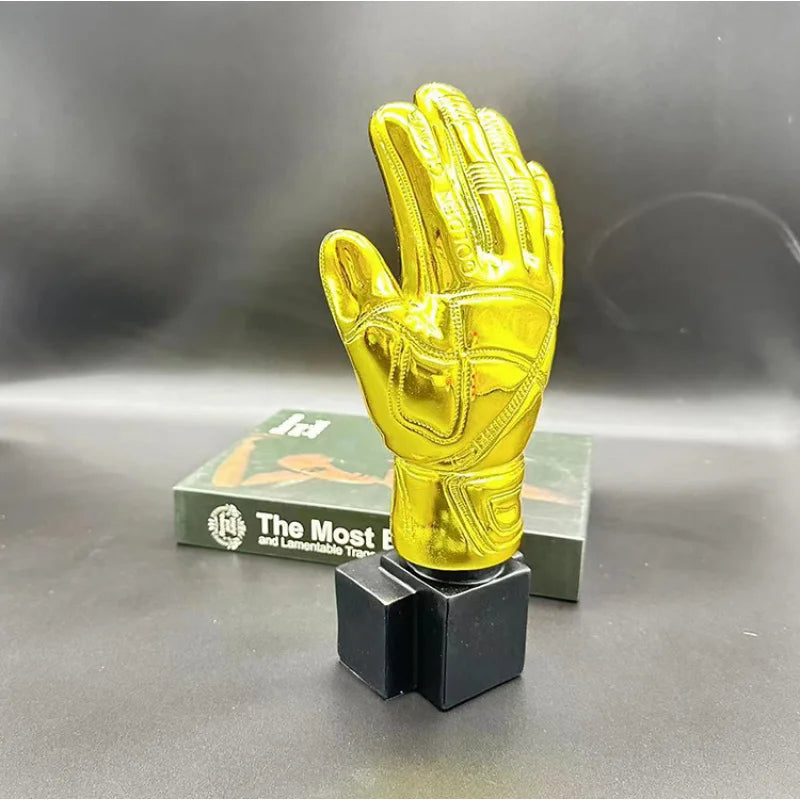 A golden glove award trophy for football fans displayed on a dark surface.