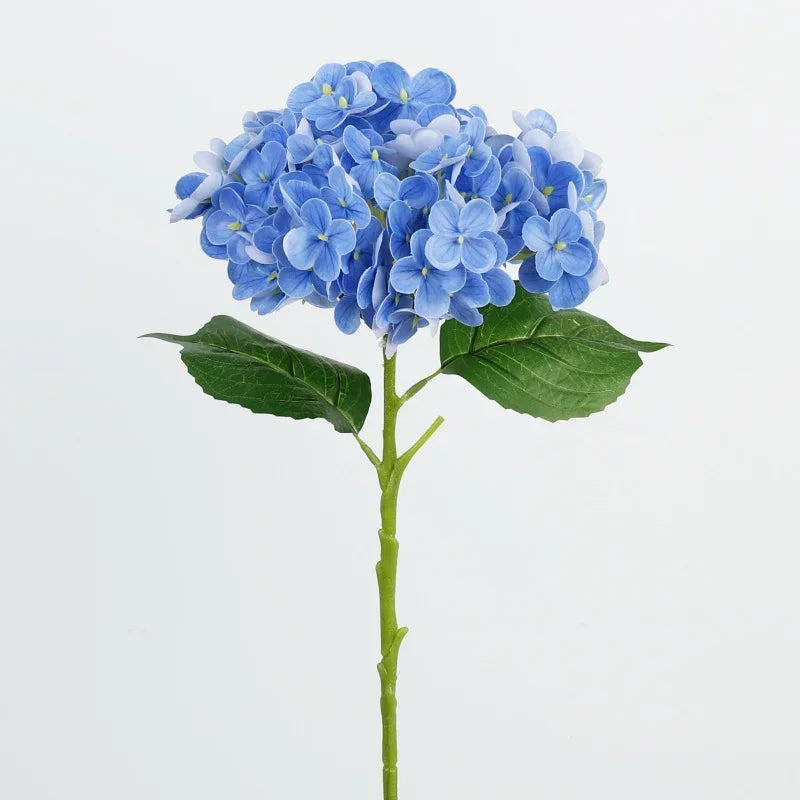 A branch of artificial blue hydrangea flowers with green leaves on a stem.