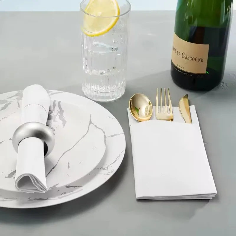 Flache Darstellung eines weißen Tellers mit gerollten Servietten, einem Glas Wasser mit Zitronenscheibe und einer Flasche Rot