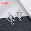 20 pieces of vintage ship anchor charms for jewelry making displayed on a dark surface.