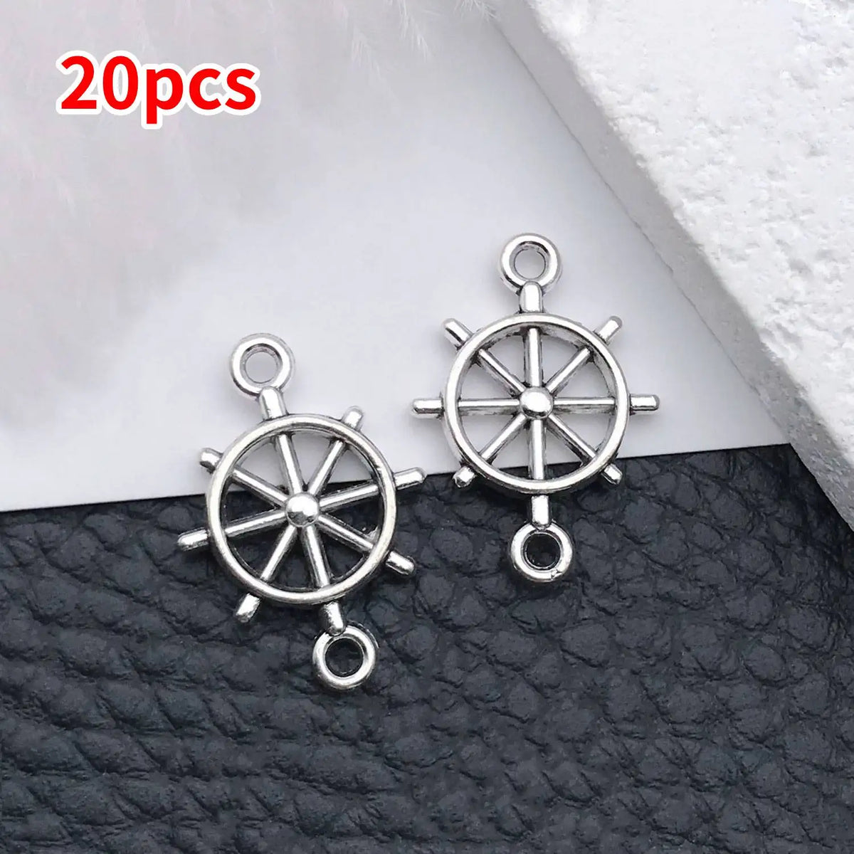 20 pieces of vintage ship anchor charms for jewelry making displayed on a dark surface.