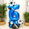 A large blue foil balloon shaped like the number 6 is decorated with black and silver balloons.