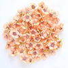 A pile of silk artificial flower heads in soft peach and pink tones for weddings and crafts.