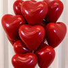 A cluster of glossy red heart-shaped latex balloons for party decoration.