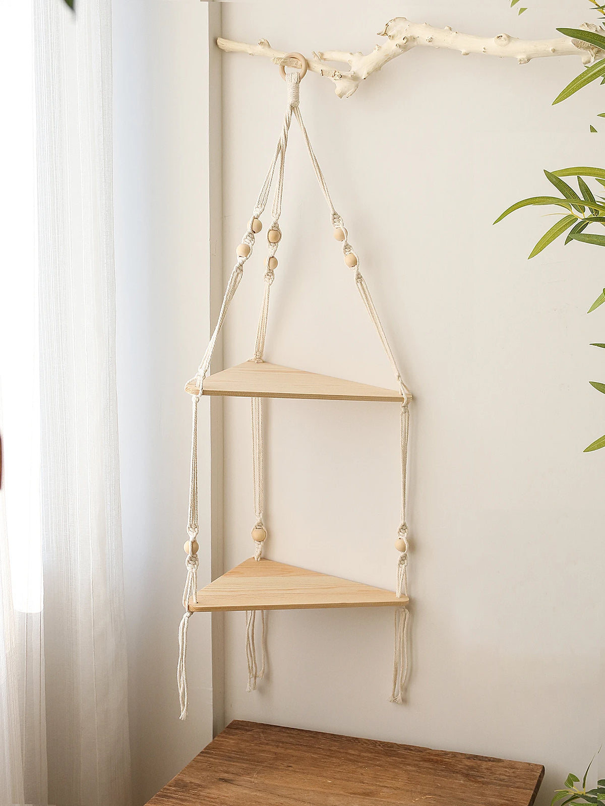 Étagère flottante en bois bohème avec crochets de ficelle naturelle montée sur un mur blanc.