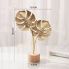 A golden ginkgo leaf metal decorative sculpture with a slender stem and round base.