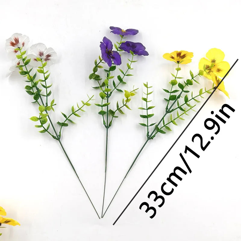 A small bouquet of artificial pansy and daisy flowers in purple, white, and yellow.