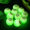 A collection of glowing green, eyeball-shaped bouncy balls with detailed patterns resting on a dark surface.