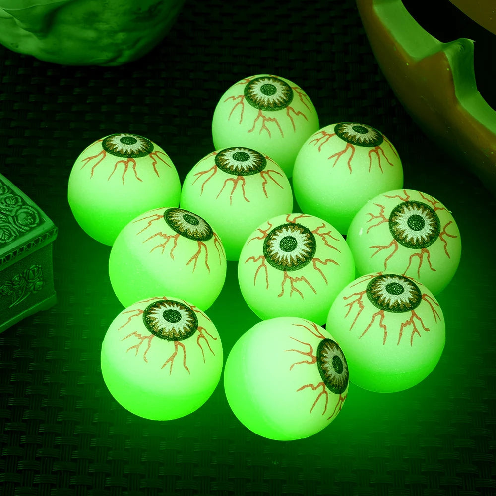 A collection of glowing green, eyeball-shaped bouncy balls with detailed patterns resting on a dark surface.