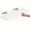 A hand is holding a white wooden floating wall shelf with metal brackets.