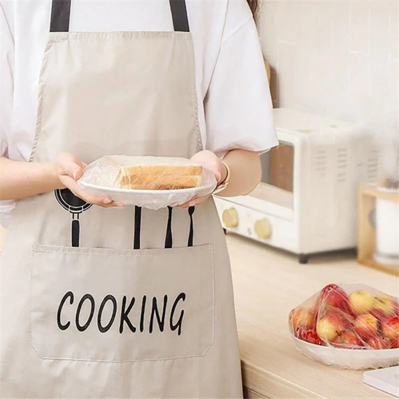 A person wearing an apron holds a glass plate with a loaf of bread, demonstrating reusable elastic food covers.