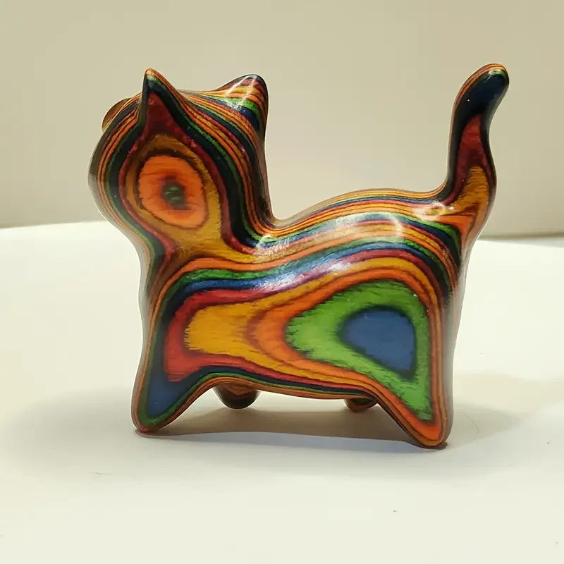 Hand-painted wooden sculpture of a kitten with vibrant, swirling stripes of color.