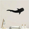 Black silhouette of a whale shark with white polka dots on a light wall.