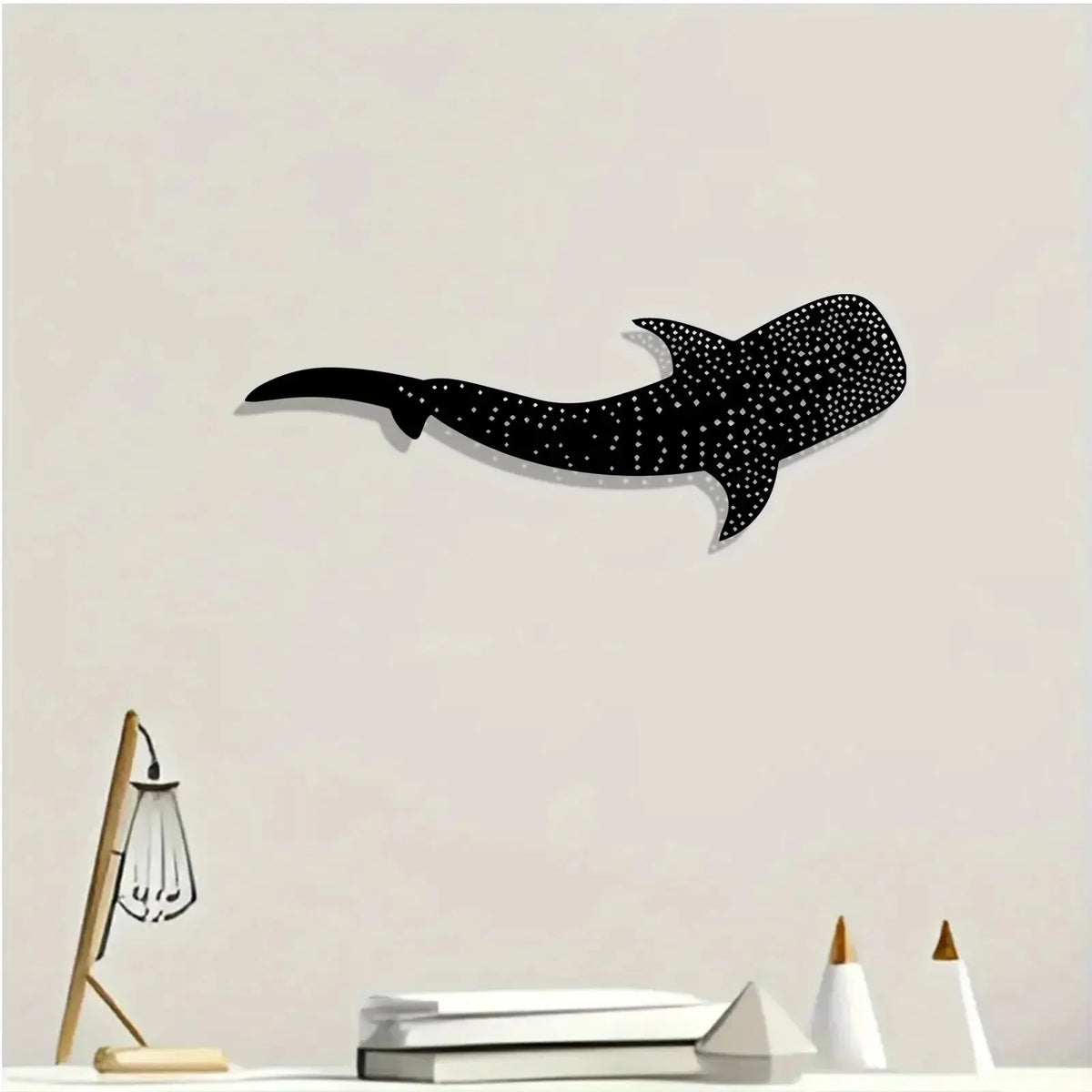 Black silhouette of a whale shark with white polka dots on a light wall.