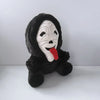 A black plush toy of Ghost Face with a white mask and a red tongue.