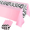 Pink cow print western tablecloth with black and white spots displayed on a table.