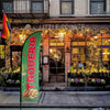 A green feather flag with the word Taqueria is displayed on a pole in front of a warmly lit restaurant facade.