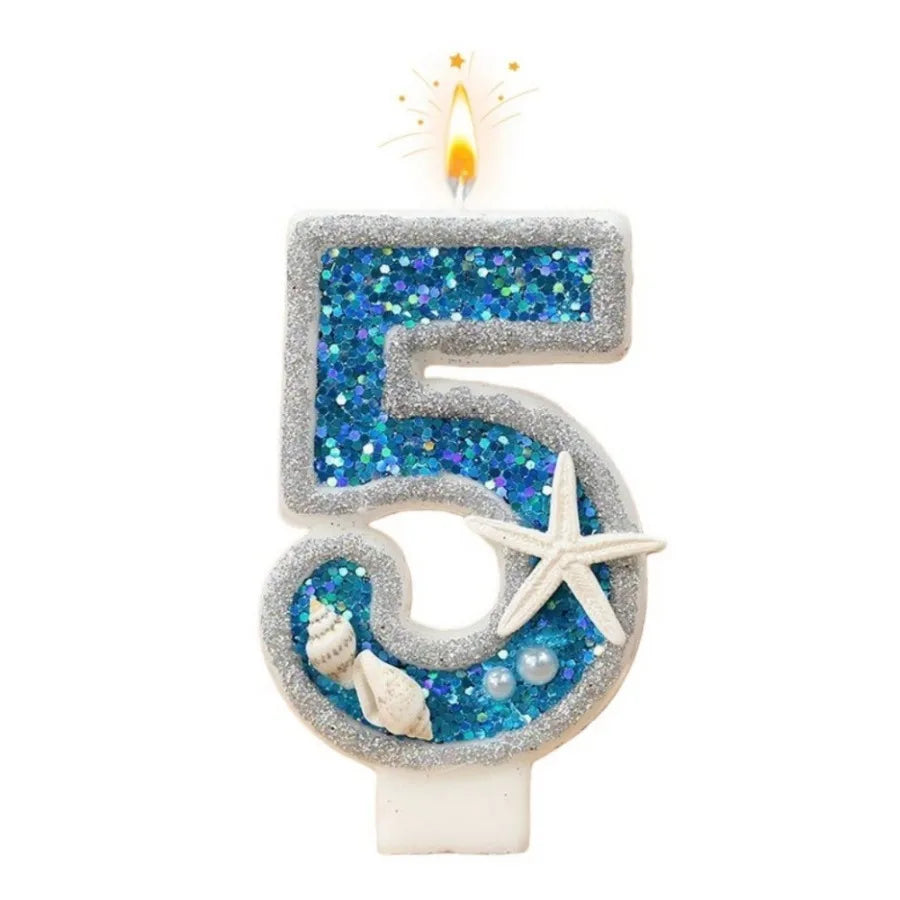 A glittery number five candle decorated with blue seawater accents and a flame.