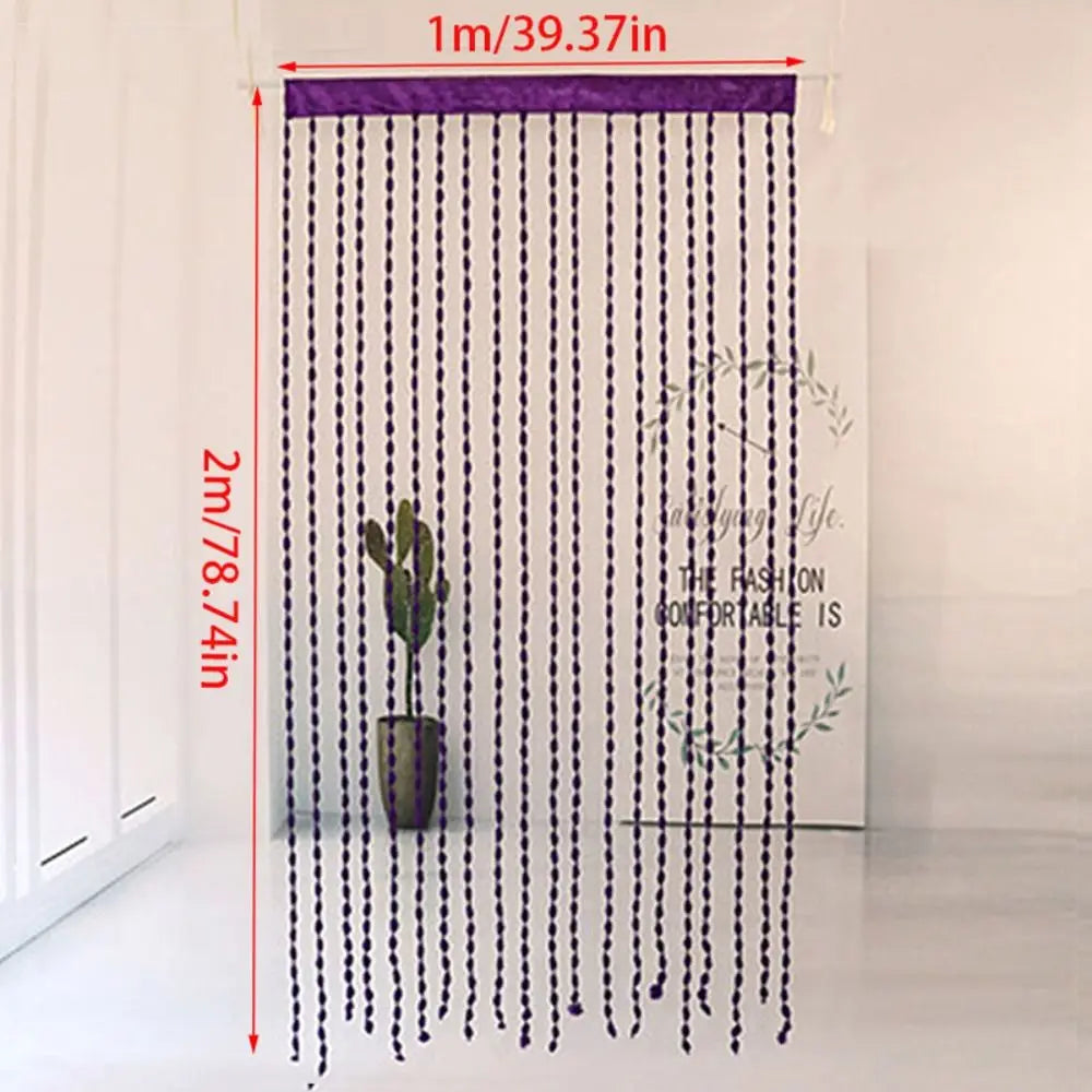 A long, purple beaded string curtain hangs vertically in a bright room.