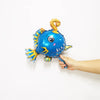 A blue and yellow foil balloon shaped like a sea creature with a curled horn.