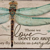 A rustic wooden sign featuring a watercolor illustration of a dragonfly with the text Those we love don't go away they fly be
