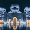 Night view of a mosque with multiple domes reflecting in water, illuminated by soft light.