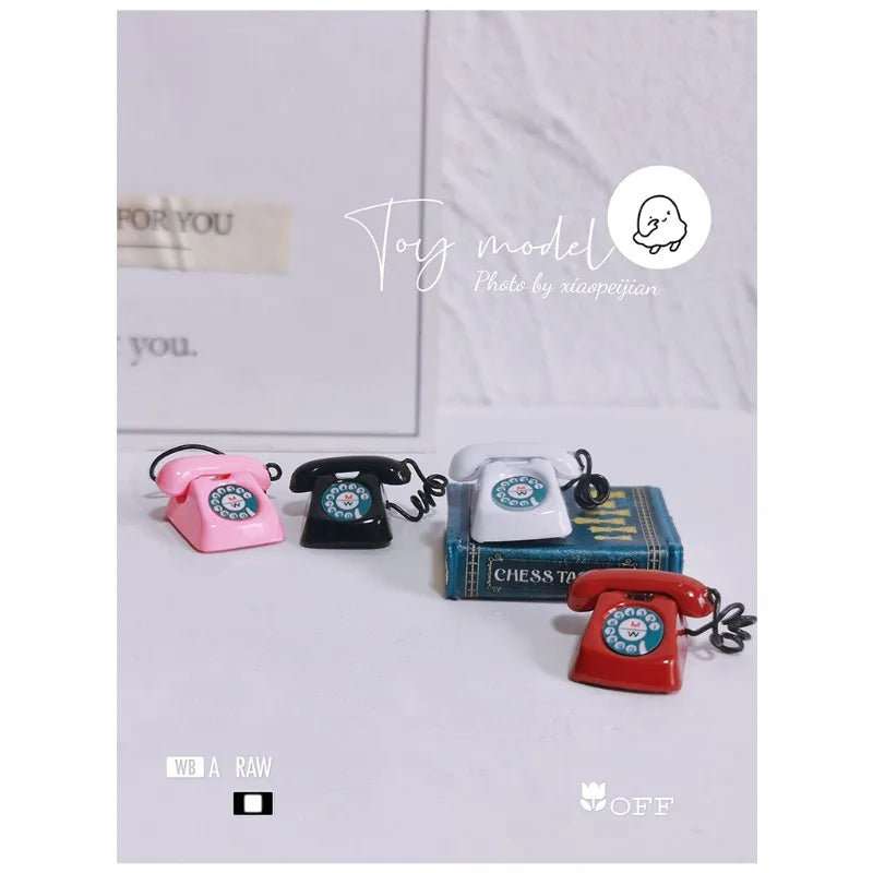 A vintage rotary desk phone miniature decor in pink, black, and red is displayed on a white surface.