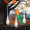 An orange pumpkin decoration hangs from a tree branch amidst autumn leaves and glowing Halloween eggs.