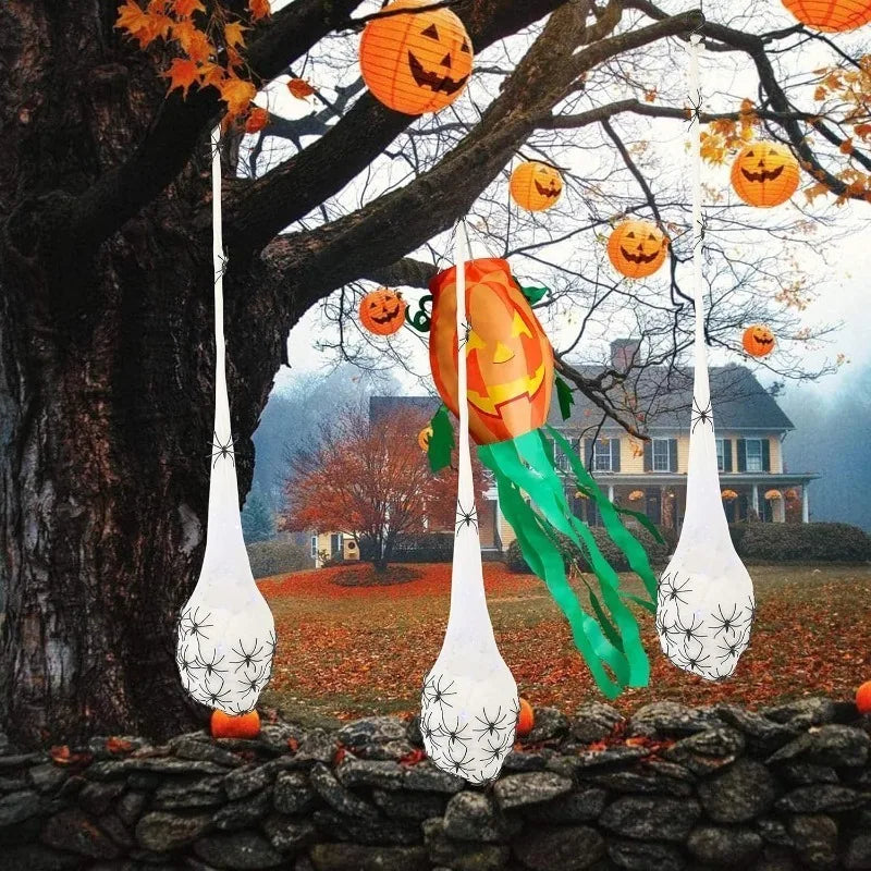 An orange pumpkin decoration hangs from a tree branch amidst autumn leaves and glowing Halloween eggs.