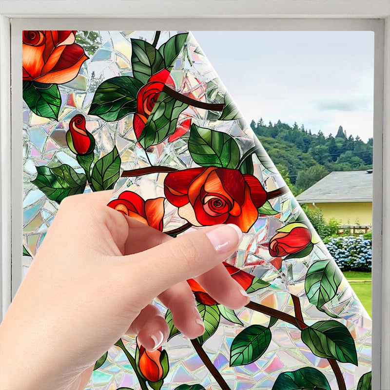 A hand touches a botanical print static cling window film featuring red roses and green leaves.