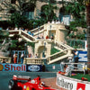 A red Formula 1 race car is speeding on a track, with a grandstand and palm trees in the background.