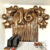 A display of leopard print star-shaped balloons hanging in front of a gold tassel curtain.