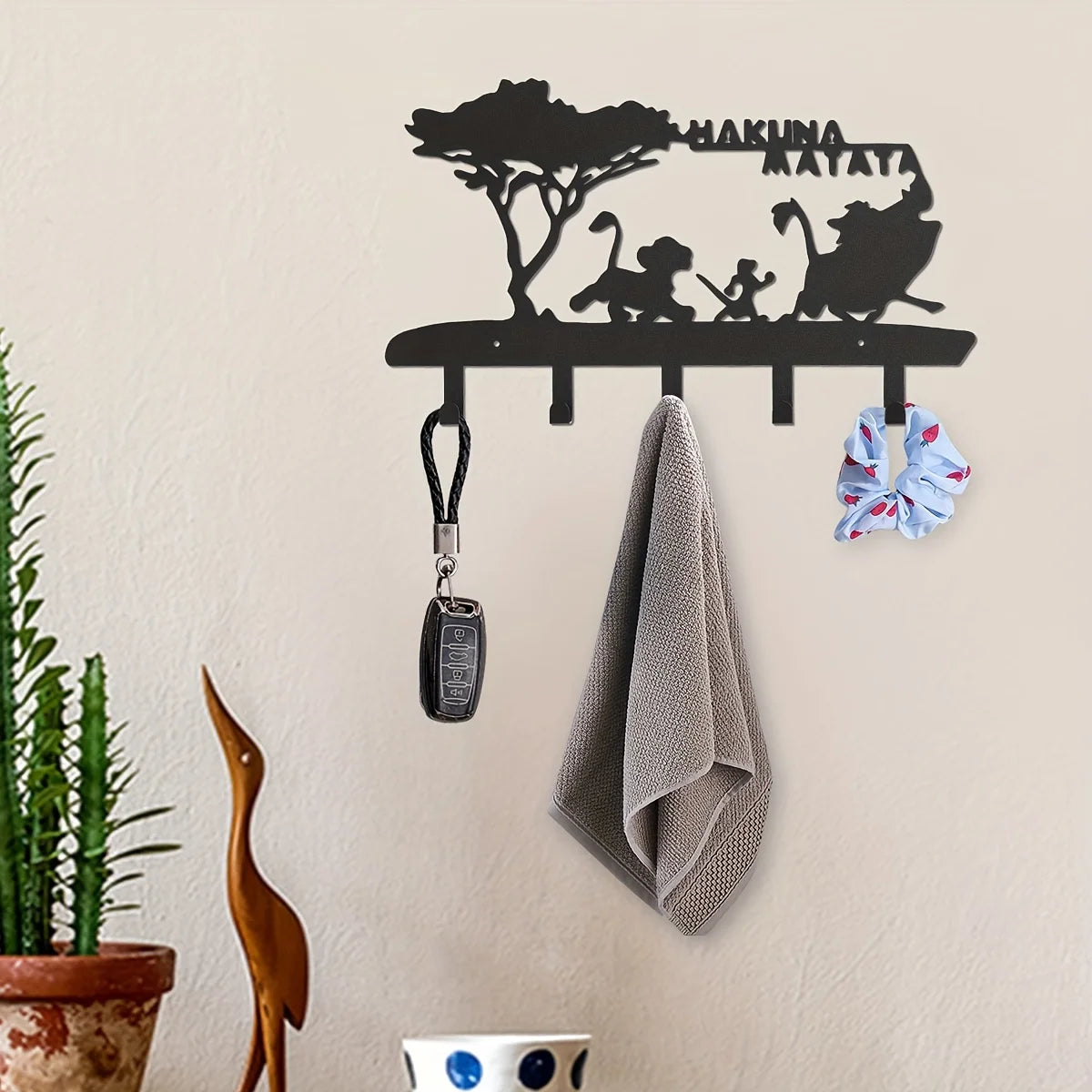 Black decorative metal key hooks mounted on a wall, with a towel and a bow visible.