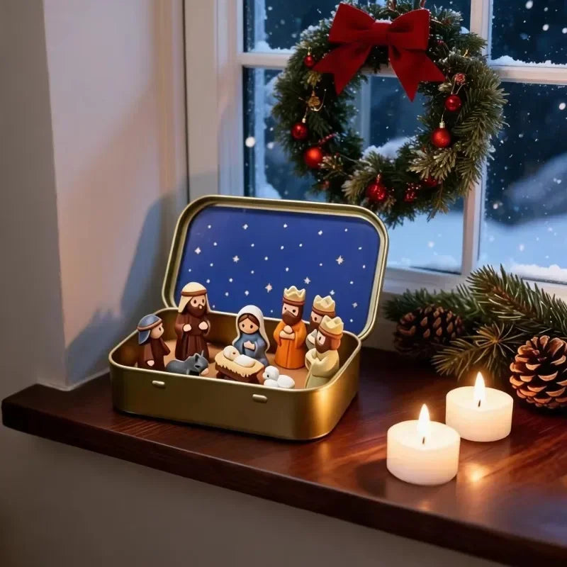 A nativity scene figurine set displayed in a gold storage box next to a decorated Christmas wreath by a window.