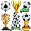 A collection of gold and black soccer-themed party décor including a trophy, a soccer ball, and a green and black soccer shoe
