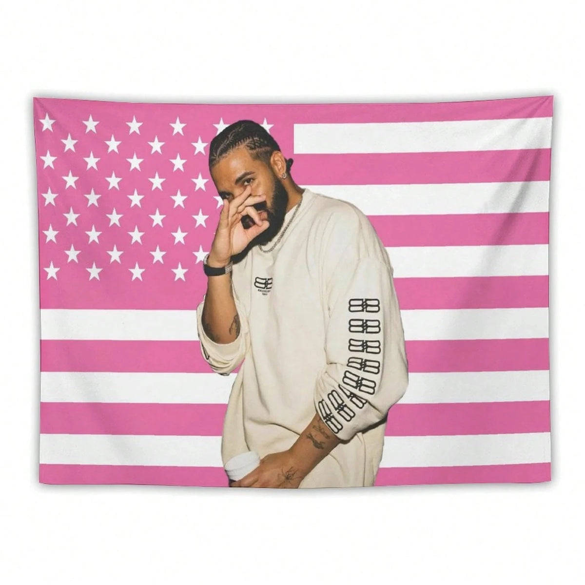Un homme à la barbe portant une chemise claire se tient devant un fond de drapeau américain rayé rose et blanc.