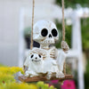 A white skull and skeleton ghost figurine hanging by twine against a blurred outdoor background.