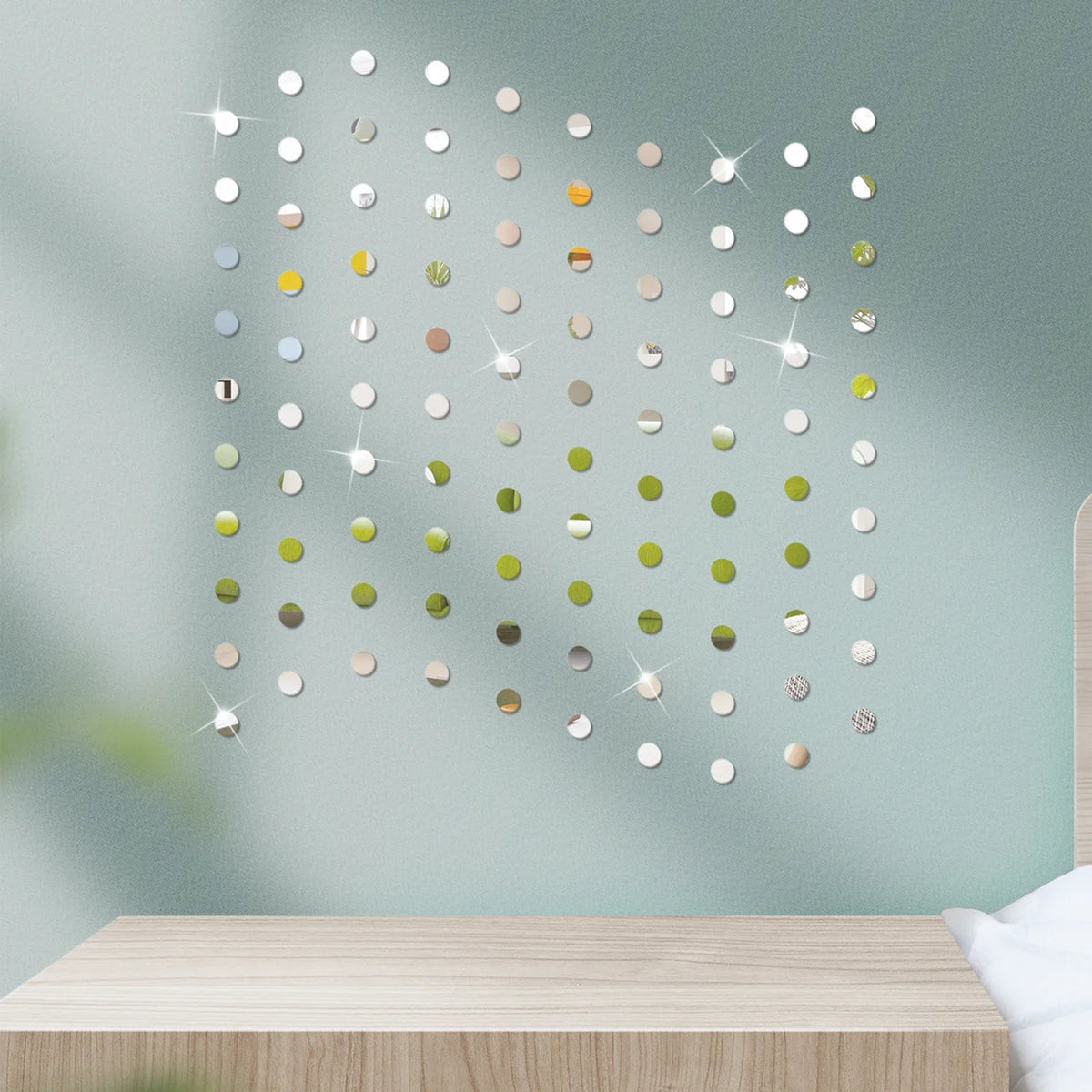 A close-up of 3D mosaic mirror wall decals featuring various gold and green circular reflective pieces on a light teal wall.