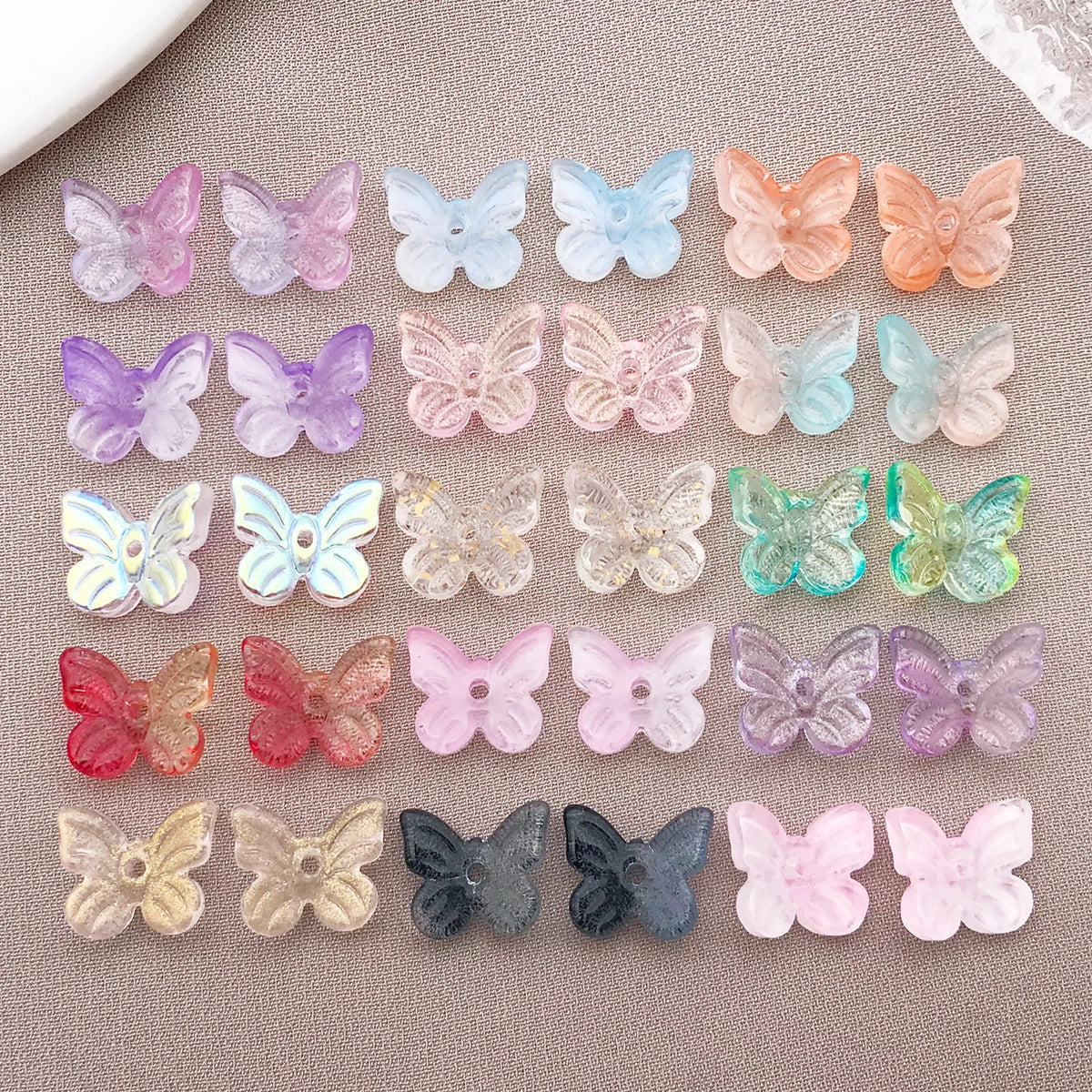 Variedad de cuentas de mariposa de vidrio coloridas en tonos rosa, púrpura, azul y naranja