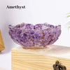 A purple amethyst crystal lotus bowl resting on a light wooden surface.