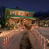 A pathway lined with red and white candy cane lights illuminates a house decorated for Christmas at night.